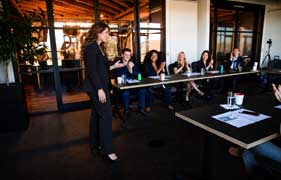Woman presenting to a group seated around a conference table